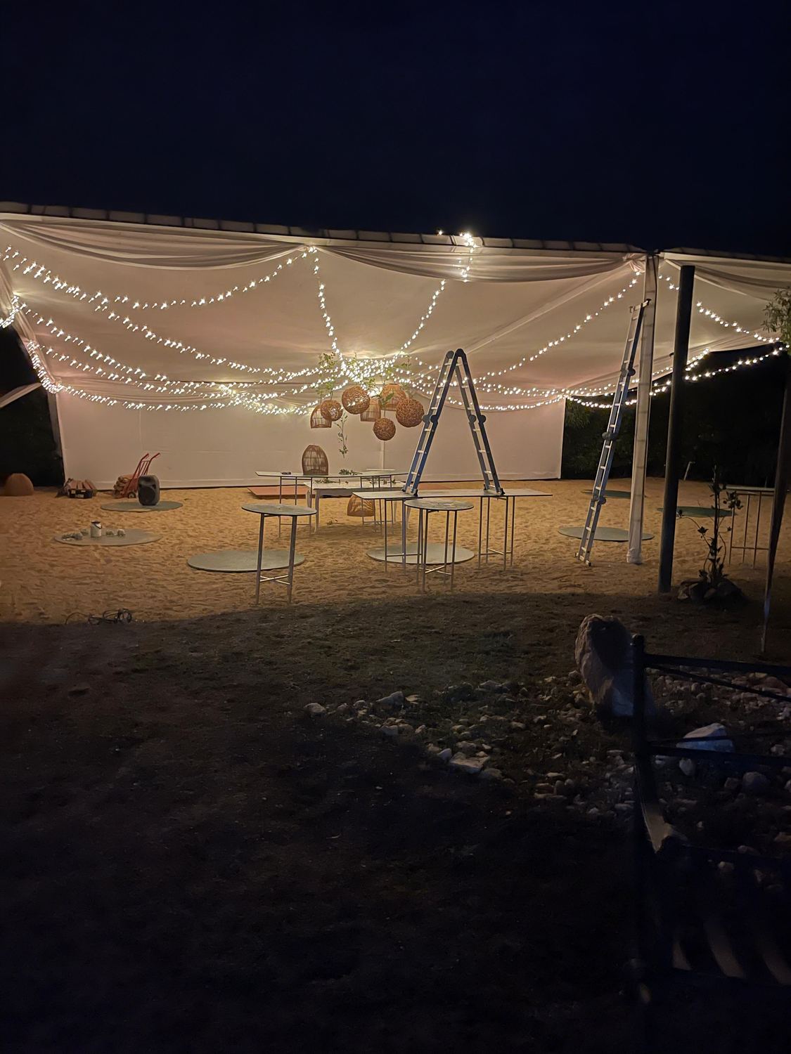 Carpa con guirnaldas de luces montada sobre la arena para un evento de noche