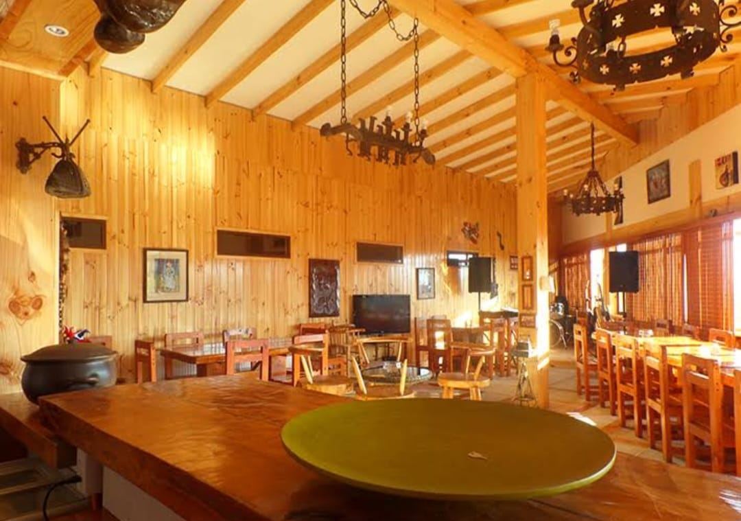 Salón comedor de madera con mesas largas y lámparas de fierro forjado