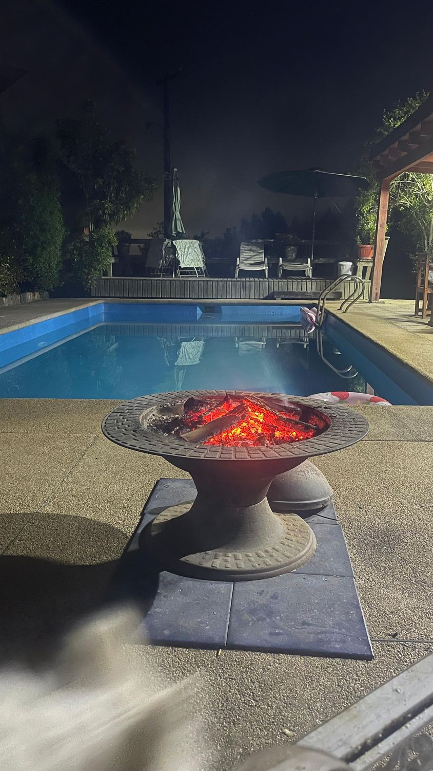 Fogón encendido junto a la piscina, de noche